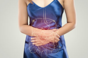 The photo of stomach and large intestine is on the woman's body against gray background, People With Stomach ache problem concept, Female anatomy
